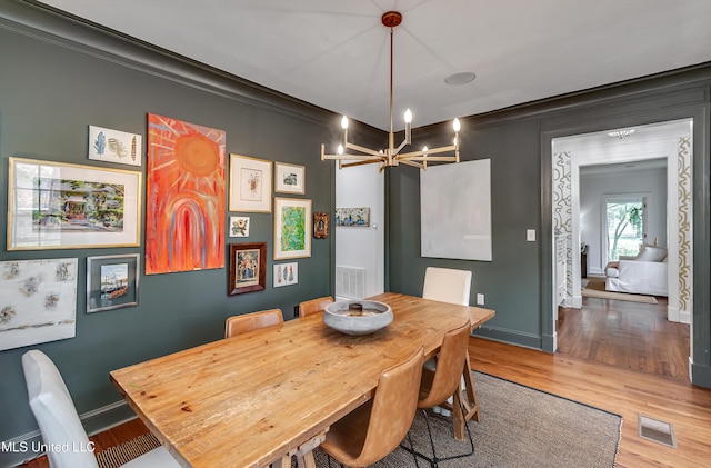 dining space featuring a notable chandelier, crown molding, and hardwood / wood-style floors