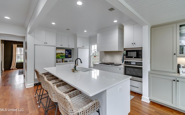 kitchen featuring appliances with stainless steel finishes, a breakfast bar area, sink, and a center island with sink