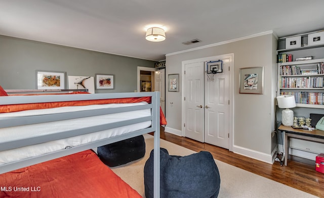 bedroom featuring crown molding, dark hardwood / wood-style flooring, and a closet