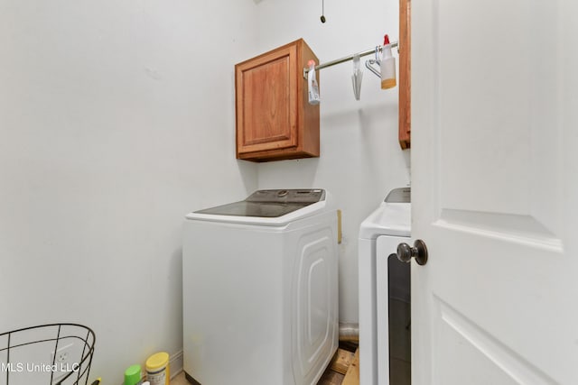 clothes washing area with washer and clothes dryer and cabinet space