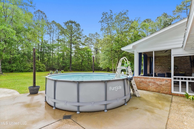 pool featuring a yard, a patio area, and a sunroom