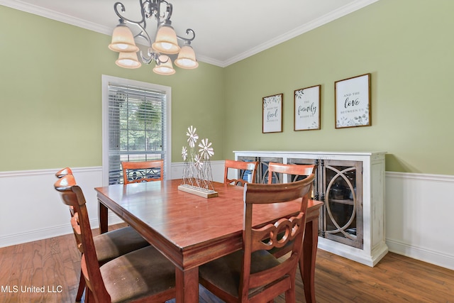 dining space featuring a chandelier, crown molding, wood finished floors, and a wainscoted wall