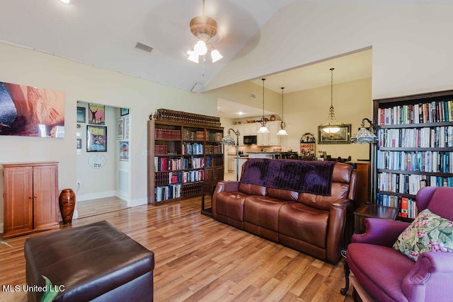 living room with light hardwood / wood-style flooring, high vaulted ceiling, and ceiling fan