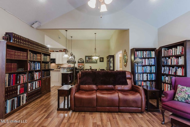 living room featuring light hardwood / wood-style flooring, high vaulted ceiling, and ceiling fan