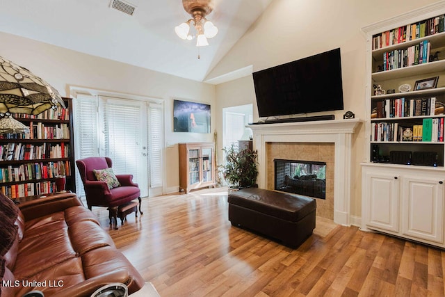 living room with light hardwood / wood-style floors, high vaulted ceiling, a fireplace, and ceiling fan