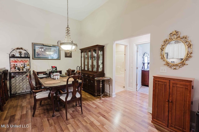 dining area with hardwood / wood-style floors and high vaulted ceiling