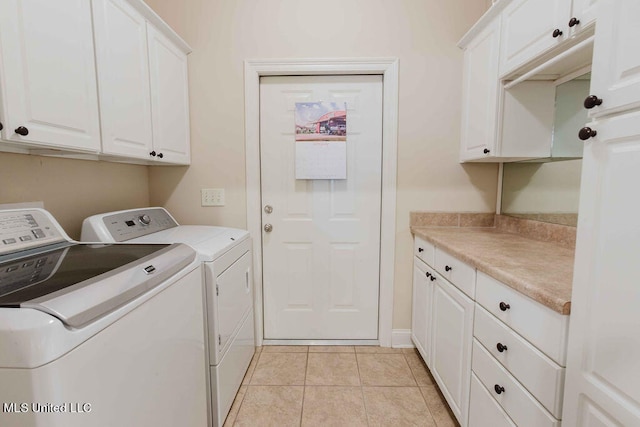 clothes washing area featuring light tile patterned flooring, cabinets, and washer and clothes dryer