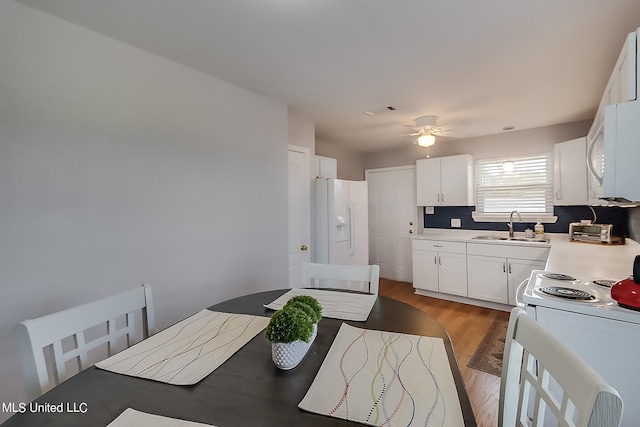 kitchen featuring dark hardwood / wood-style flooring, white cabinets, sink, ceiling fan, and white appliances