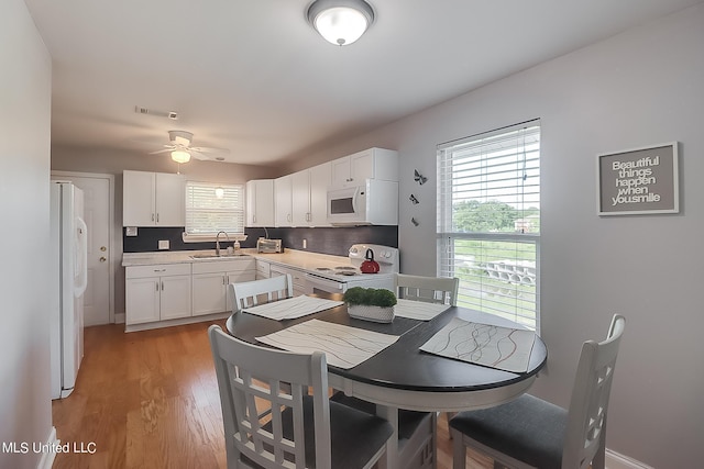 kitchen with light hardwood / wood-style floors, sink, ceiling fan, white cabinetry, and white appliances