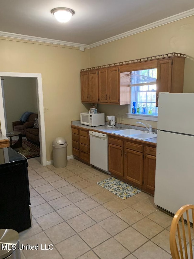 kitchen with a sink, light tile patterned floors, brown cabinetry, white appliances, and ornamental molding