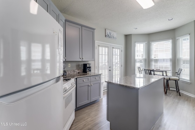 2252 Beach Dr Unit 602, Gulfport, MS 39507 - kitchen featuring white appliances, gray cabinetry, light wood-type flooring, light stone countertops, and a textured ceiling