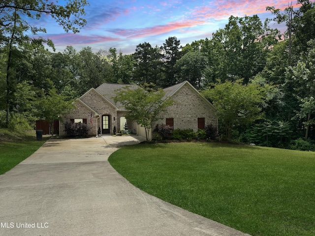 view of front of property featuring driveway, a yard, and brick siding