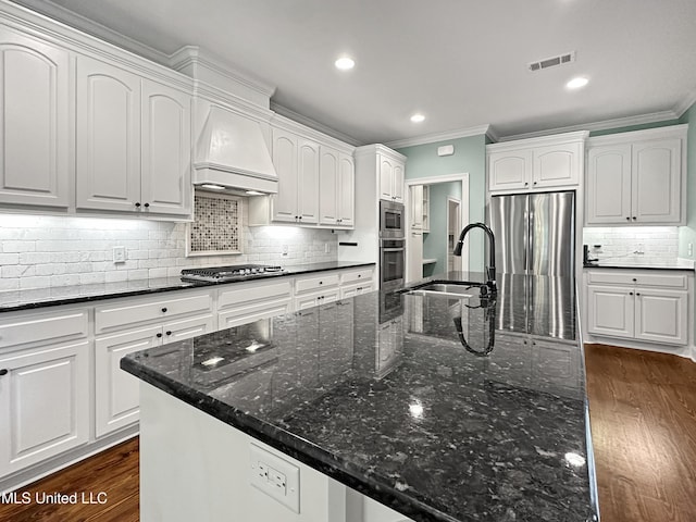 kitchen featuring a sink, custom exhaust hood, ornamental molding, appliances with stainless steel finishes, and dark wood finished floors