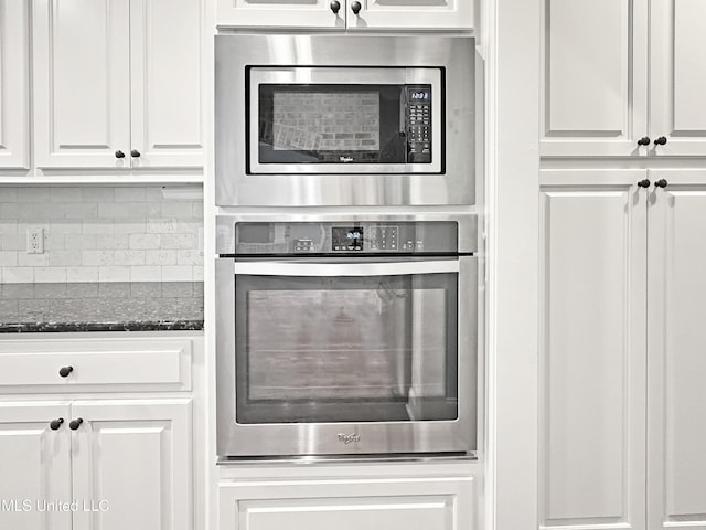 kitchen with appliances with stainless steel finishes, white cabinets, tasteful backsplash, and dark stone countertops