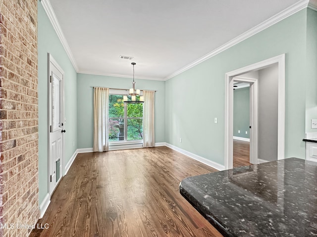 unfurnished dining area featuring dark wood finished floors, crown molding, baseboards, and brick wall