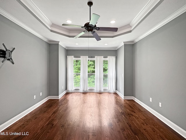 unfurnished room with a tray ceiling, wood finished floors, ceiling fan, baseboards, and crown molding