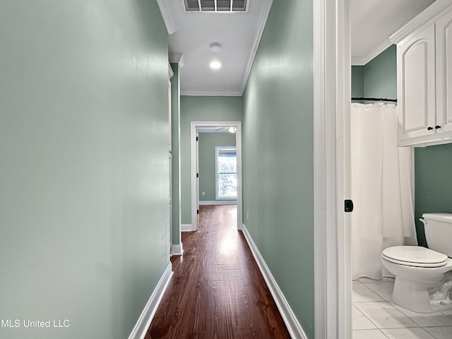 corridor featuring ornamental molding, baseboards, and wood finished floors