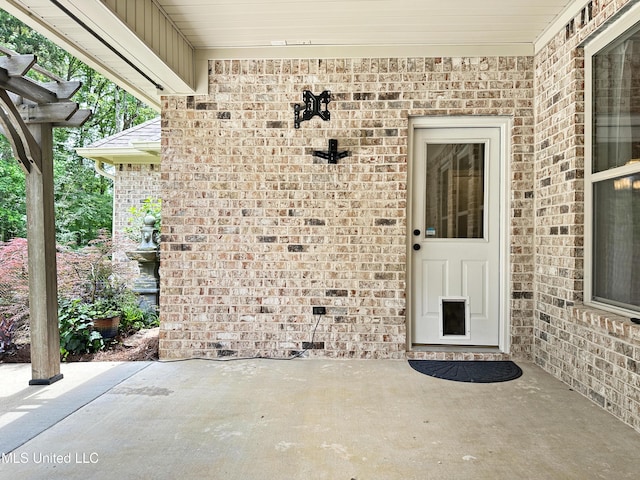 doorway to property with brick siding and a patio