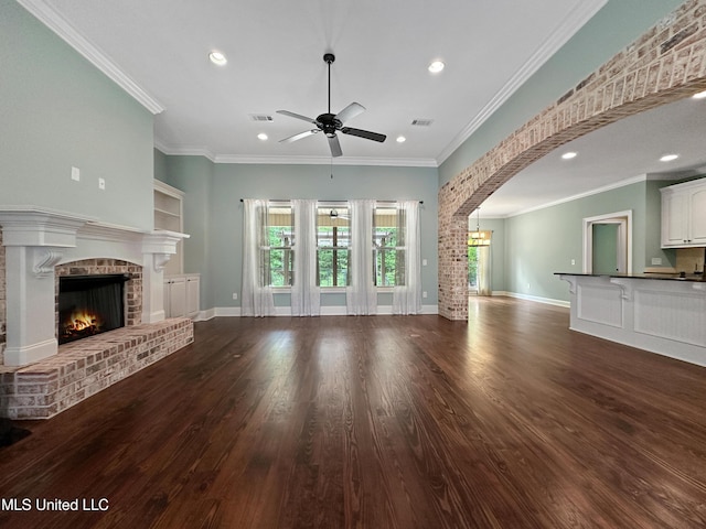 unfurnished living room with ceiling fan, a brick fireplace, wood finished floors, recessed lighting, and ornamental molding