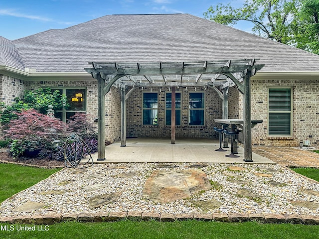 rear view of property with brick siding, roof with shingles, a pergola, and a patio area