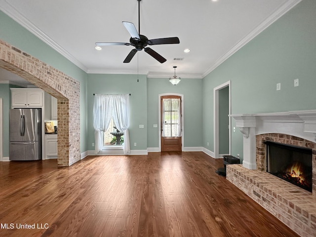 unfurnished living room with a brick fireplace, a ceiling fan, ornamental molding, dark wood-style floors, and recessed lighting