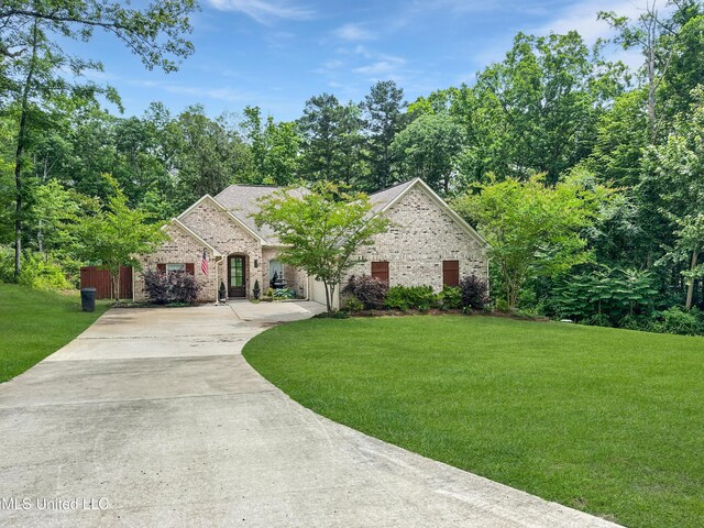 french country inspired facade featuring concrete driveway, a front lawn, and brick siding