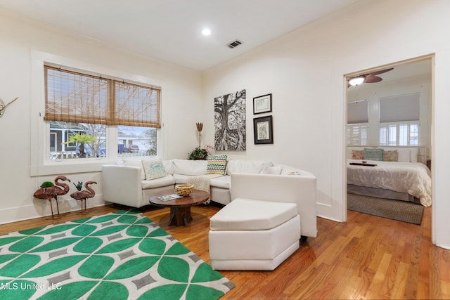 living room with ornamental molding and light hardwood / wood-style flooring