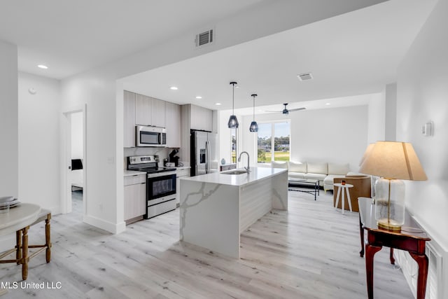 1302 Magnolia St Unit A101, Gulfport, MS 39507 - kitchen featuring appliances with stainless steel finishes, modern cabinets, light wood-type flooring, ceiling fan, and decorative light fixtures