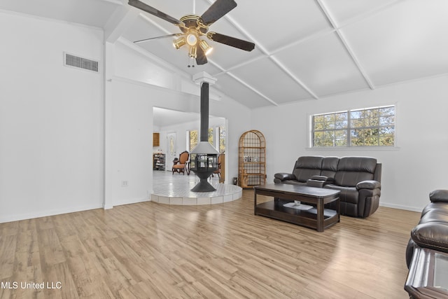 unfurnished living room featuring a wood stove, ceiling fan, light hardwood / wood-style floors, and vaulted ceiling