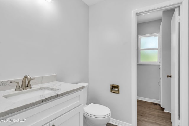 bathroom with visible vents, wood finished floors, vanity, baseboards, and toilet