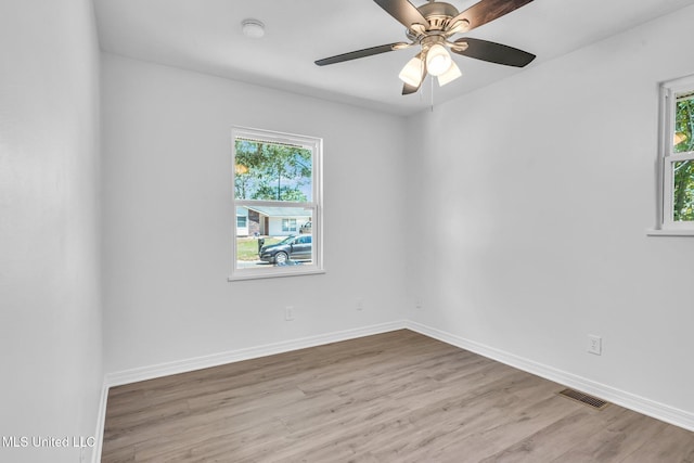 empty room featuring ceiling fan, baseboards, visible vents, and wood finished floors