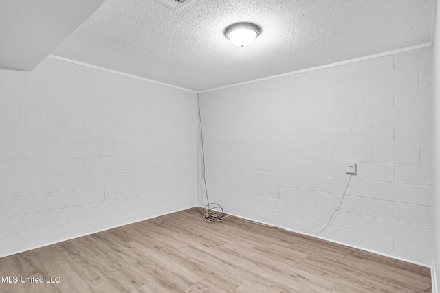 spare room featuring a textured ceiling, ornamental molding, and wood finished floors