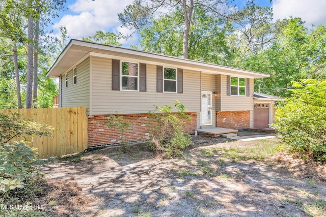 bi-level home featuring brick siding, an attached garage, and fence