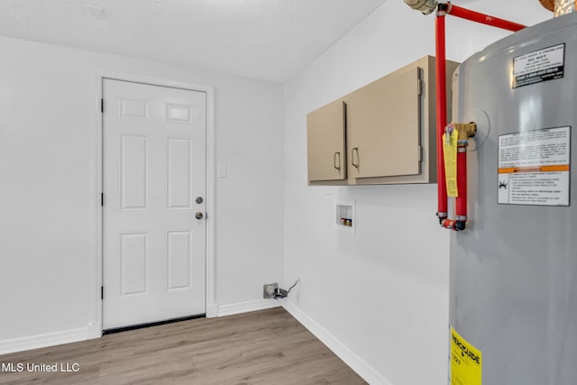 laundry area with washer hookup, cabinet space, baseboards, light wood finished floors, and water heater