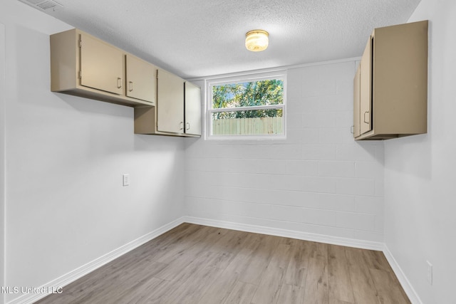 interior space with baseboards, light wood-style flooring, a textured ceiling, and visible vents