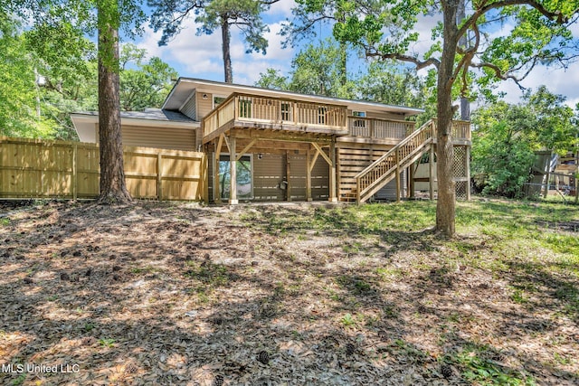 rear view of property featuring a fenced backyard, a wooden deck, and stairway
