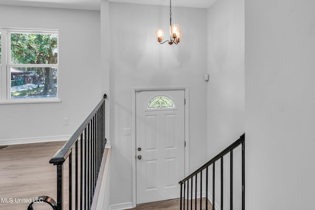foyer with baseboards, a notable chandelier, wood finished floors, and a wealth of natural light