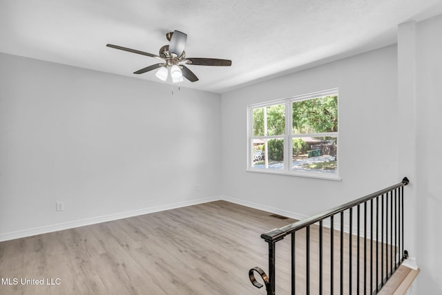 spare room featuring baseboards, a ceiling fan, wood finished floors, and visible vents
