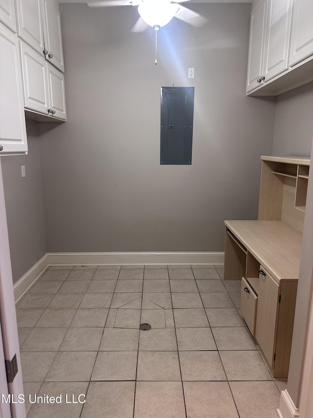 clothes washing area with electric panel, baseboards, light tile patterned floors, and ceiling fan