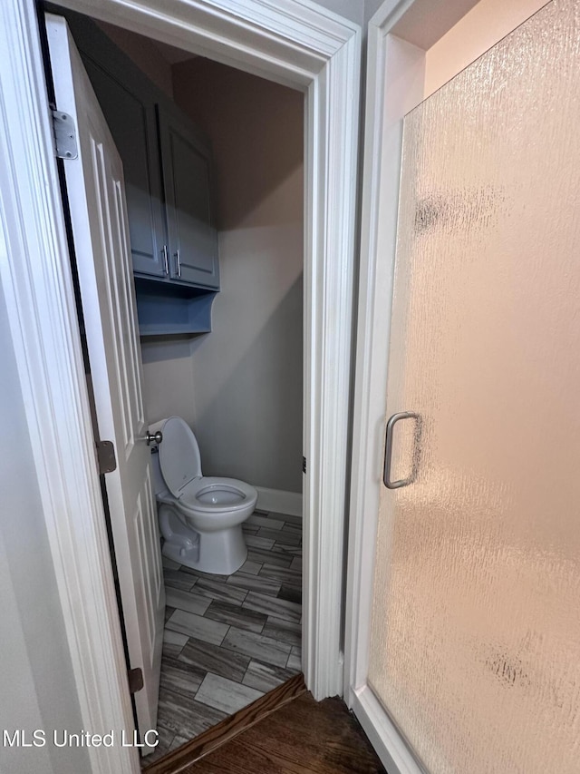 bathroom featuring toilet, baseboards, and wood finish floors