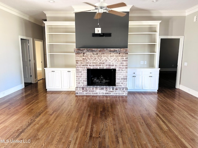 unfurnished living room with baseboards, a brick fireplace, wood finished floors, and crown molding