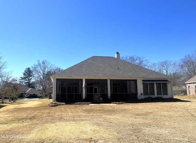 back of property with roof with shingles, a chimney, and a sunroom