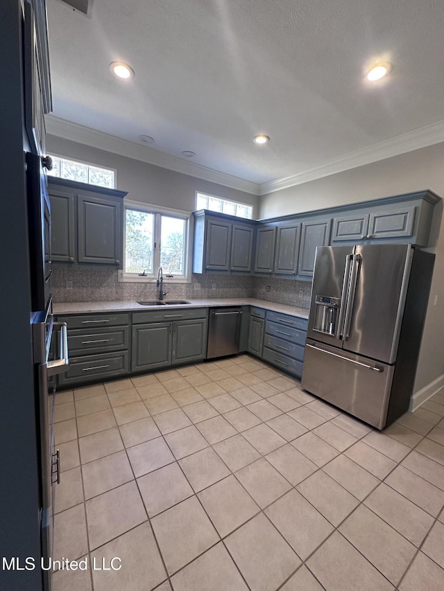 kitchen featuring ornamental molding, a sink, backsplash, stainless steel appliances, and light countertops