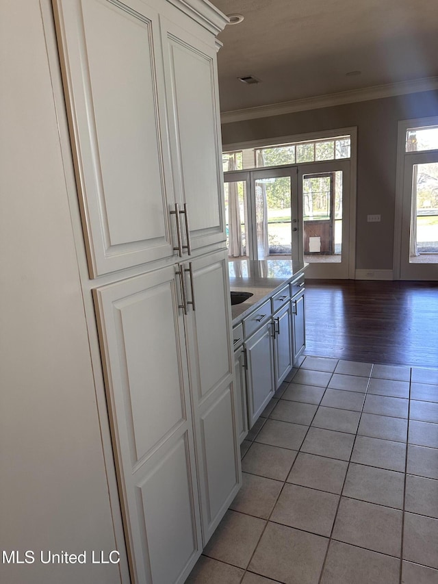 kitchen with white cabinetry, crown molding, light tile patterned floors, and french doors