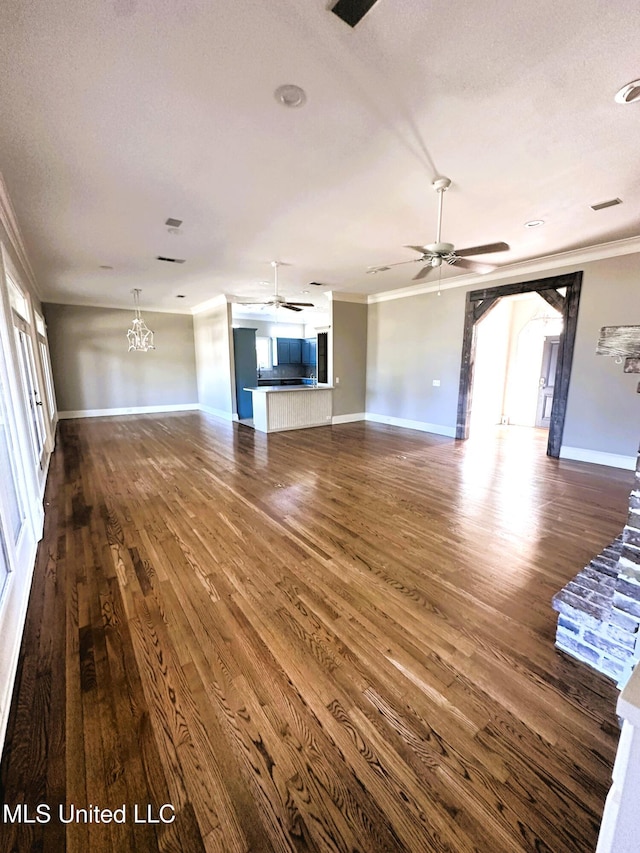 unfurnished living room featuring dark wood-style floors, baseboards, a textured ceiling, crown molding, and ceiling fan with notable chandelier