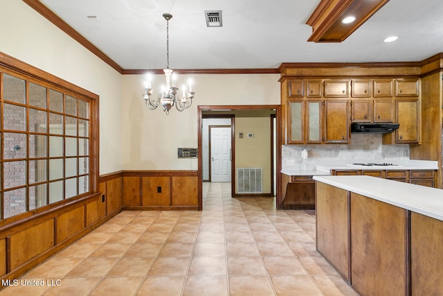 kitchen featuring exhaust hood, hanging light fixtures, backsplash, crown molding, and an inviting chandelier