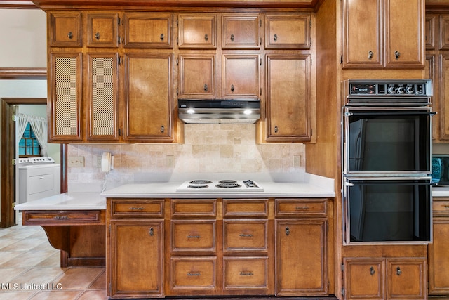 kitchen featuring double oven, decorative backsplash, washer / clothes dryer, white stovetop, and light tile patterned floors