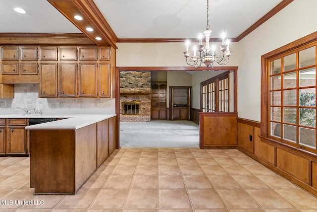 kitchen with hanging light fixtures, ornamental molding, a brick fireplace, an inviting chandelier, and wood walls