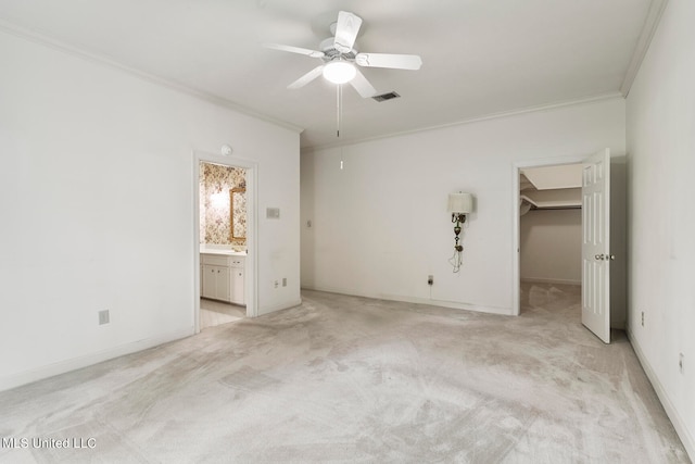 unfurnished bedroom featuring connected bathroom, a closet, a walk in closet, ornamental molding, and ceiling fan