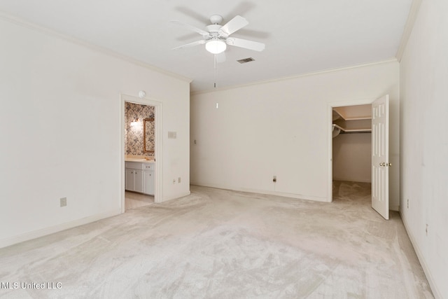 unfurnished bedroom with a spacious closet, a closet, ceiling fan, connected bathroom, and ornamental molding